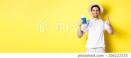 Tourism and vacation. Satisfied male tourist showing passport with tickets and thumb up, recommending travel company, standing over yellow background Tourism and vacation. Satisfied male tourist showing passport with tickets and thumb up, recommending travel company, standing over yellow background 100222535