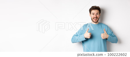 Excited smiling man showing thumbs up to praise excellent product, looking amazed and happy at camera, recommending good deal, standing on white background Excited smiling man showing thumbs up to praise excellent product, looking amazed and happy at camera, recommending good deal, standing on white background 100222602