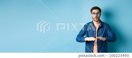 Funny guy trying sunglasses at eyewear store, dancing and having fun, standing on blue background 100223493