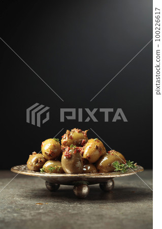 Spicy green olives in olive oil on a black background. 100226617