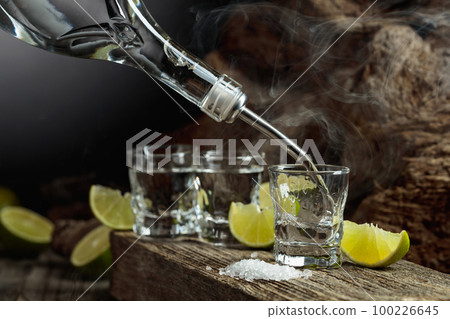 Tequila is poured from a bottle into a glass. Tequila is poured from a bottle into a glass. 100226645