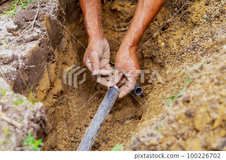During installation of underground sprinkler system to water garden an yard man worked with pipes in ground During installation of underground sprinkler system to water garden an yard man worked with pipes in ground 100226702