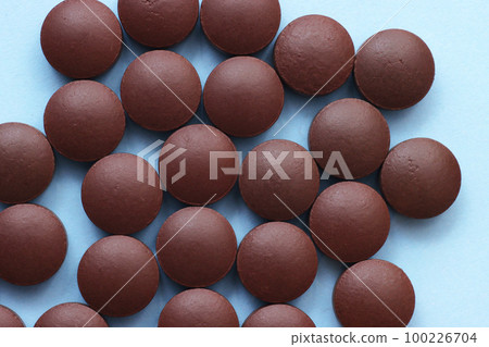 Brown pills on a blue background top view. 100226704