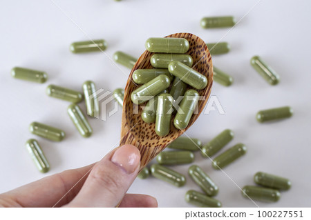 Transparent capsules with green powder inside. Useful dietary supplements with crucifers. 100227551