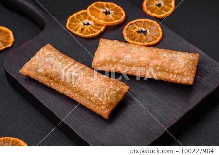 Delicious fresh crispy pie with cherry jam on a wooden cutting board 100227984