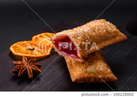 Delicious fresh crispy pie with cherry jam on a wooden cutting board 100228002