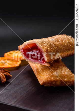 Delicious fresh crispy pie with cherry jam on a wooden cutting board Delicious fresh crispy pie with cherry jam on a wooden cutting board 100228003