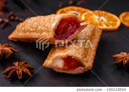 Delicious fresh crispy pie with cherry jam on a wooden cutting board Delicious fresh crispy pie with cherry jam on a wooden cutting board 100228004