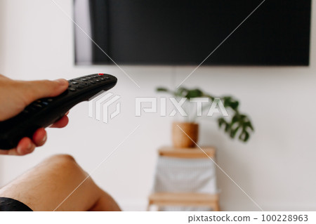 Hand holding remote point at tv. Concept of watching tv. Hand holding remote point at tv. Concept of watching tv. 100228963