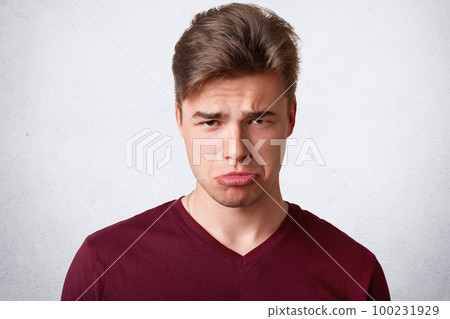 Photo of discontent gloomy male purses lower lip, looks with displeased expression, has sullen expression, going to cry after having big failure in life, expresses negative emotions, isolated on white Photo of discontent gloomy male purses lower lip, looks with displeased expression, has sullen expression, going to cry after having big failure in life, expresses negative emotions, isolated on white 100231929