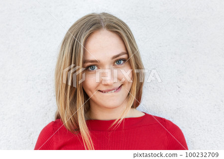Close-up portrait of beautiful female with soft eyes biting her lower lip having self-doubt being happy to hear some pleasant news. Woman with dimples expressing uncertainty while looking in camera 100232709