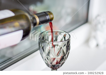 Red wine pouring from bottle. Wine glass with red wine. Alcohol drinks. Celebraion background. Wine from bottleneck. Bar background. Red wine pouring from bottle. Wine glass with red wine. Alcohol drinks. Celebraion background. Wine from bottleneck. Bar background. 100232928