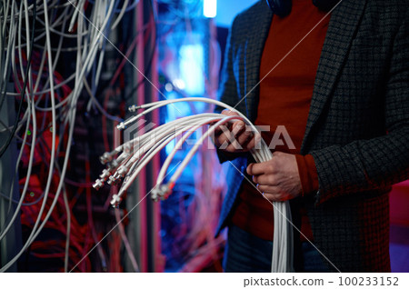 IT man with bunch of cables in hands in server room 100233152