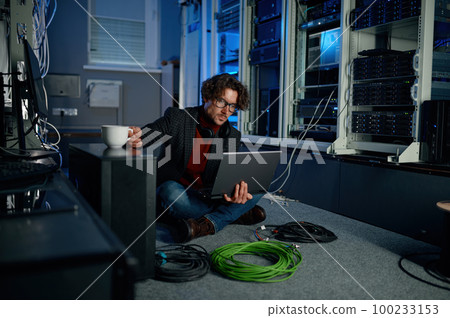 IT technician using laptop while working in data center IT technician using laptop while working in data center 100233153