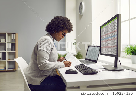 Female bookkeeper making financial report in spreadsheet in office Female bookkeeper making financial report in spreadsheet in office 100234159