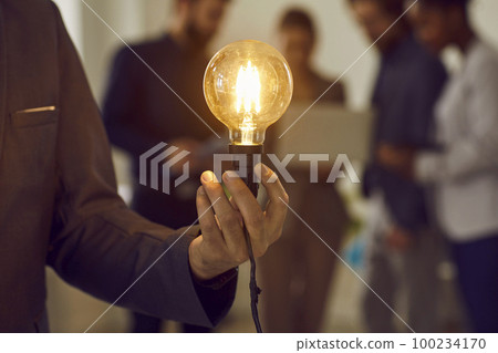 Glowing electric light bulb in hand of unknown smart and successful businessman dressed in suit. Glowing electric light bulb in hand of unknown smart and successful businessman dressed in suit. 100234170