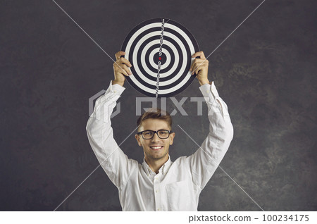 Happy young man holding shooting target to show concept of setting business goals Happy young man holding shooting target to show concept of setting business goals 100234175