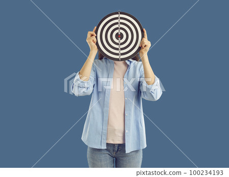 Woman holding shooting target in front of her face illustrating concept of target audience Woman holding shooting target in front of her face illustrating concept of target audience 100234193