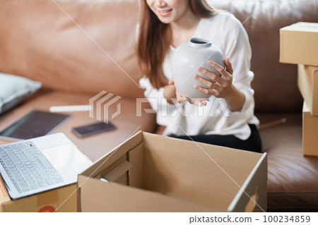 Starting small business entrepreneur of independent young Asian woman online seller using a computer showing products to a customer before making a purchase decision. SME delivery concept. 100234859