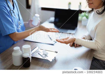Portrait of a female doctor giving medicine to an elderly patient Portrait of a female doctor giving medicine to an elderly patient 100234883