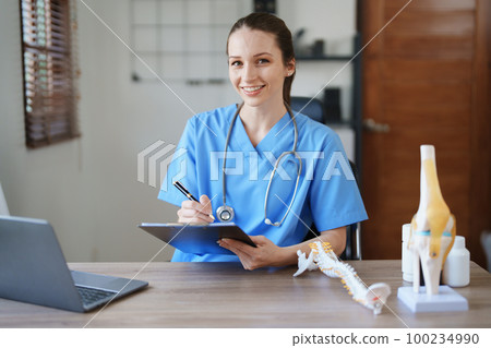 Portrait of a female doctor Center of Excellence from Orthopedic Center are using computers and documents to analyze the patient's condition before treatment 100234990