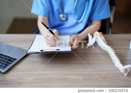 Portrait of a female doctor Center of Excellence from Orthopedic Center are using computers and documents to analyze the patient's condition before treatment 100235019