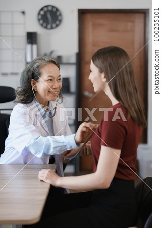Portrait of a female doctor using a stethoscope to check the pulse of an elderly patient 100235101