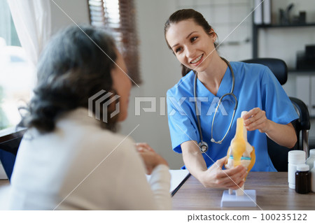Portrait of a female doctor talking to an elderly patient about osteoarthritis 100235122