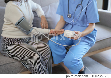 Portrait of female doctor measuring patient's blood pressure before treatment 100235128