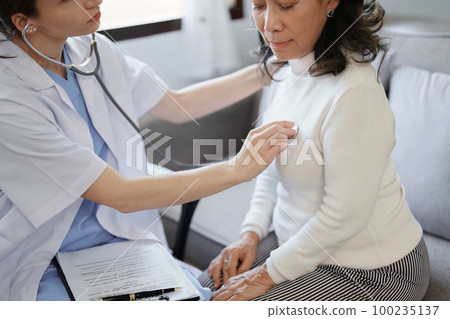 Portrait of a female doctor using a stethoscope to check the pulse of an elderly patient 100235137