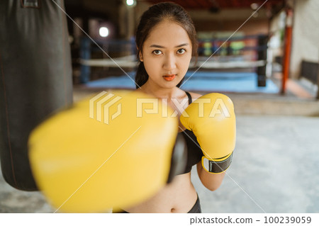 a beautiful boxer with yellow boxing gloves standing with punching moves a beautiful boxer with yellow boxing gloves standing with punching moves 100239059