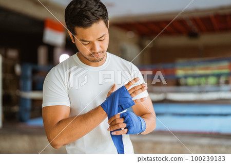 a asian male boxer wearing the boxing gloves while standing in ring 100239183