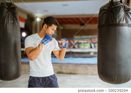 boxer seriously punching the heavy bags in the ring boxer seriously punching the heavy bags in the ring 100239204