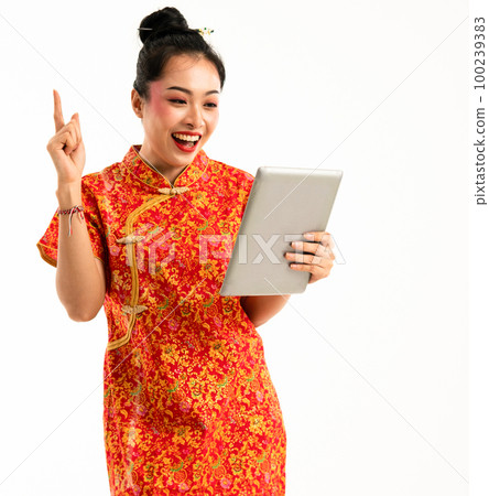 beautiful asian woman in red cheongsam standing look at the tablet beautiful asian woman in red cheongsam standing look at the tablet 100239383