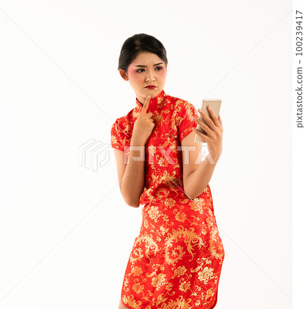 a beautiful woman in red cheongsam standing look at the phone a beautiful woman in red cheongsam standing look at the phone 100239417