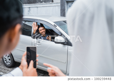 male driver in a car waves as he meets customers male driver in a car waves as he meets customers 100239448