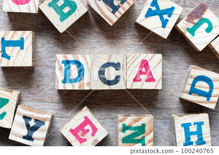 Alphabet letter block in word DCA (Abbreviation of Dollar-cost averaging) and another letter on wood background 100240765