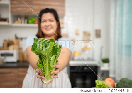 Asian Pregnant learn how to cook healthy meals from the Internet in kitchen, Fat women prepare a vegetable salad for diet food and lose weight. Concept of healthy eating 100244846