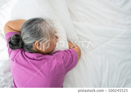 Senior woman with gray hair in bed feel depressed or suffering from strong headache migraine and high blood pressure, insomniac trying to sleep disturbed toss and turn in bedroom 100245525