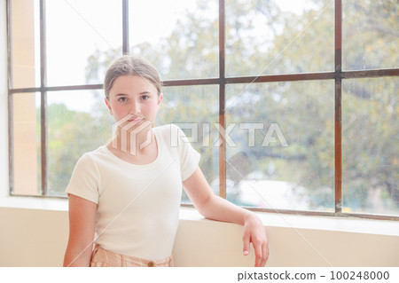 Australian girl leaning against window and looking at camera 100248000