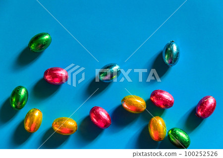 Easter chocolate eggs in foil on blue background. Top view Easter chocolate eggs in foil on blue background. Top view 100252526