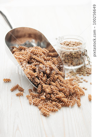 Green lentil fusilli pasta on a wooden background. 100256649