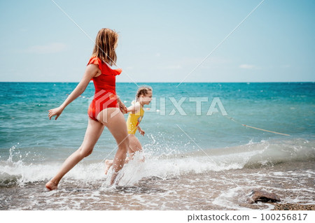 Happy loving family mother and daughter having fun together on the beach. Mum playing with her kid in holiday vacation next to the ocean - Family lifestyle and love concept Happy loving family mother and daughter having fun together on the beach. Mum playing with her kid in holiday vacation next to the ocean - Family lifestyle and love concept 100256817