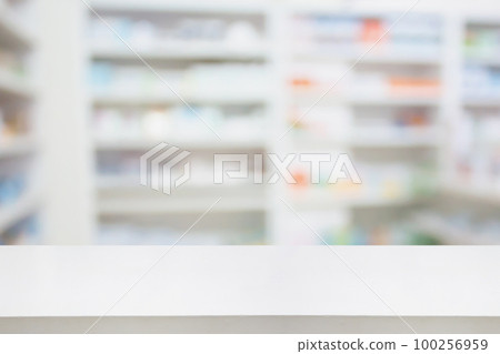 Pharmacy drugstore counter table with blur abstract backbround with medicine and healthcare product on shelves 100256959