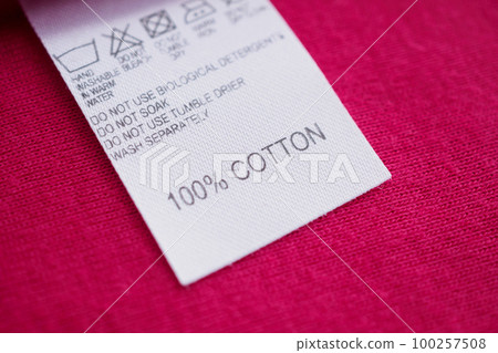White laundry care washing instructions clothes label on red cotton shirt White laundry care washing instructions clothes label on red cotton shirt 100257508