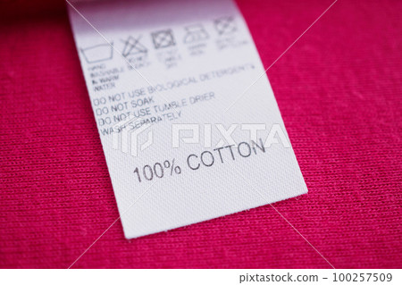 White laundry care washing instructions clothes label on red cotton shirt White laundry care washing instructions clothes label on red cotton shirt 100257509