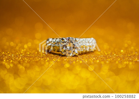 Jewelry wedding diamond ring on golden glitter bokeh light background Jewelry wedding diamond ring on golden glitter bokeh light background 100258882