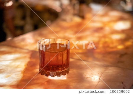 A glass of cocktail on illuminated counter bar 100259602