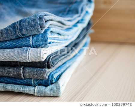 denim blue jeans stack on wood table background denim blue jeans stack on wood table background 100259748