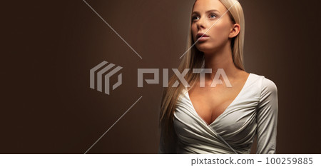 Wide studio portrait of a beautiful woman in white dress looking away 100259885